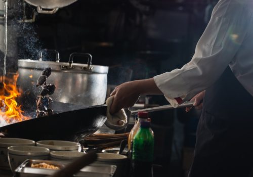 Chef stir fry in wok. Dramatic cooking with fire hard at kitchen
